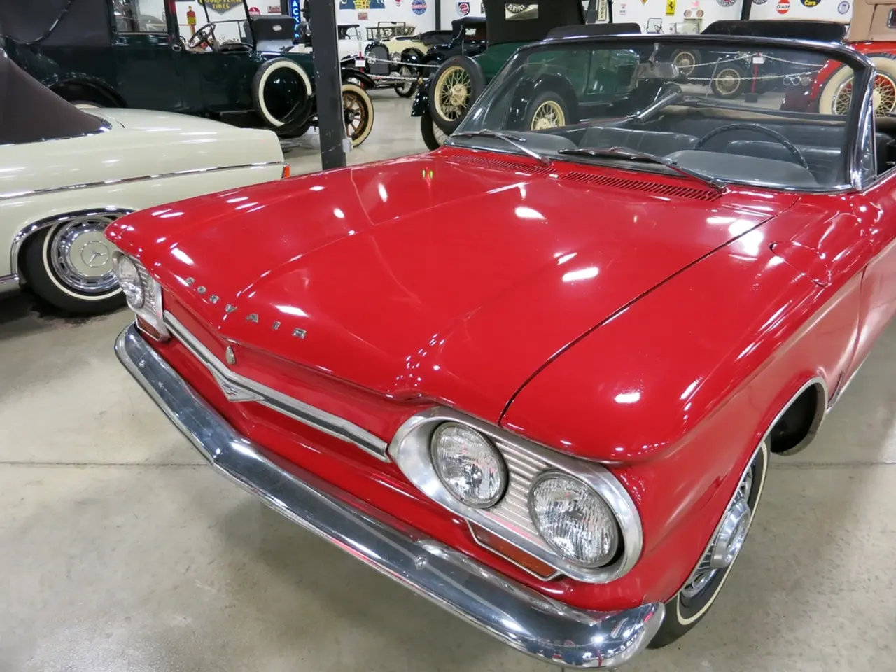 In this image I see number of vintage cars which are of different in colors and I see the floor. In...