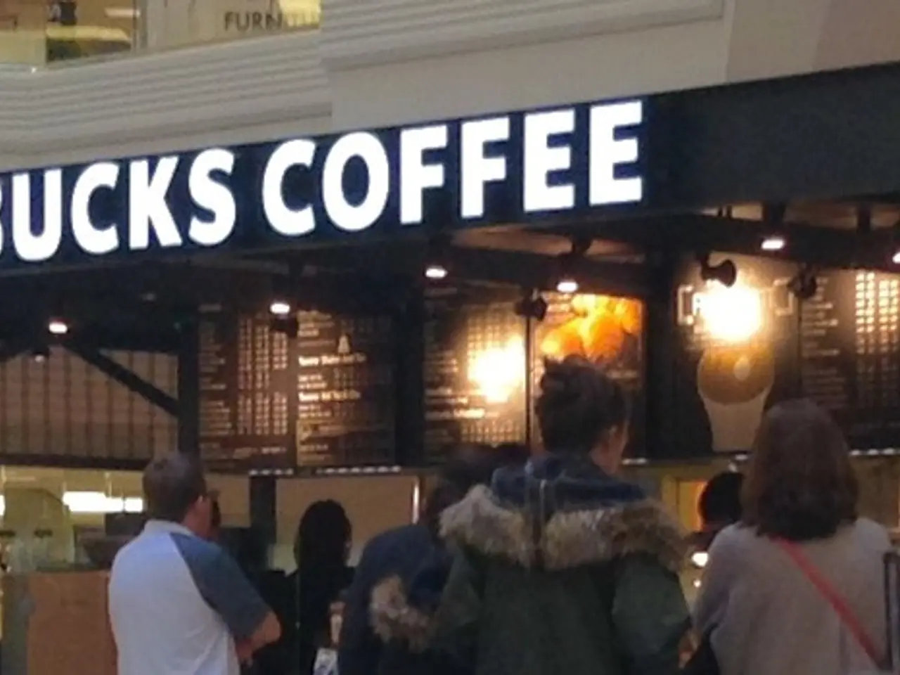 In front of the image there are people standing. In front of them there is a coffee shop. At the...