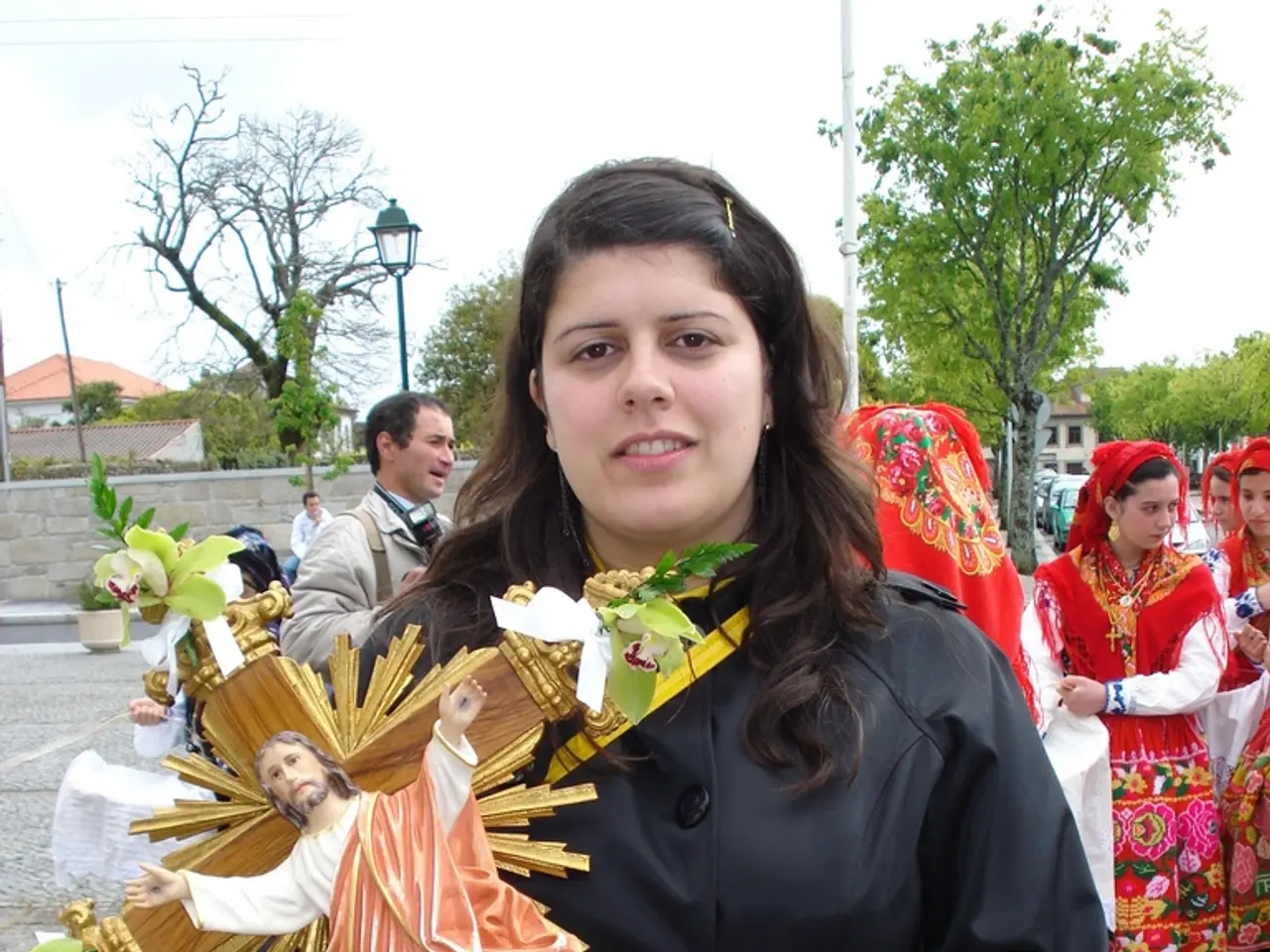 In front of the image there is a woman holding Jesus Christ depiction in her hand, behind the woman...