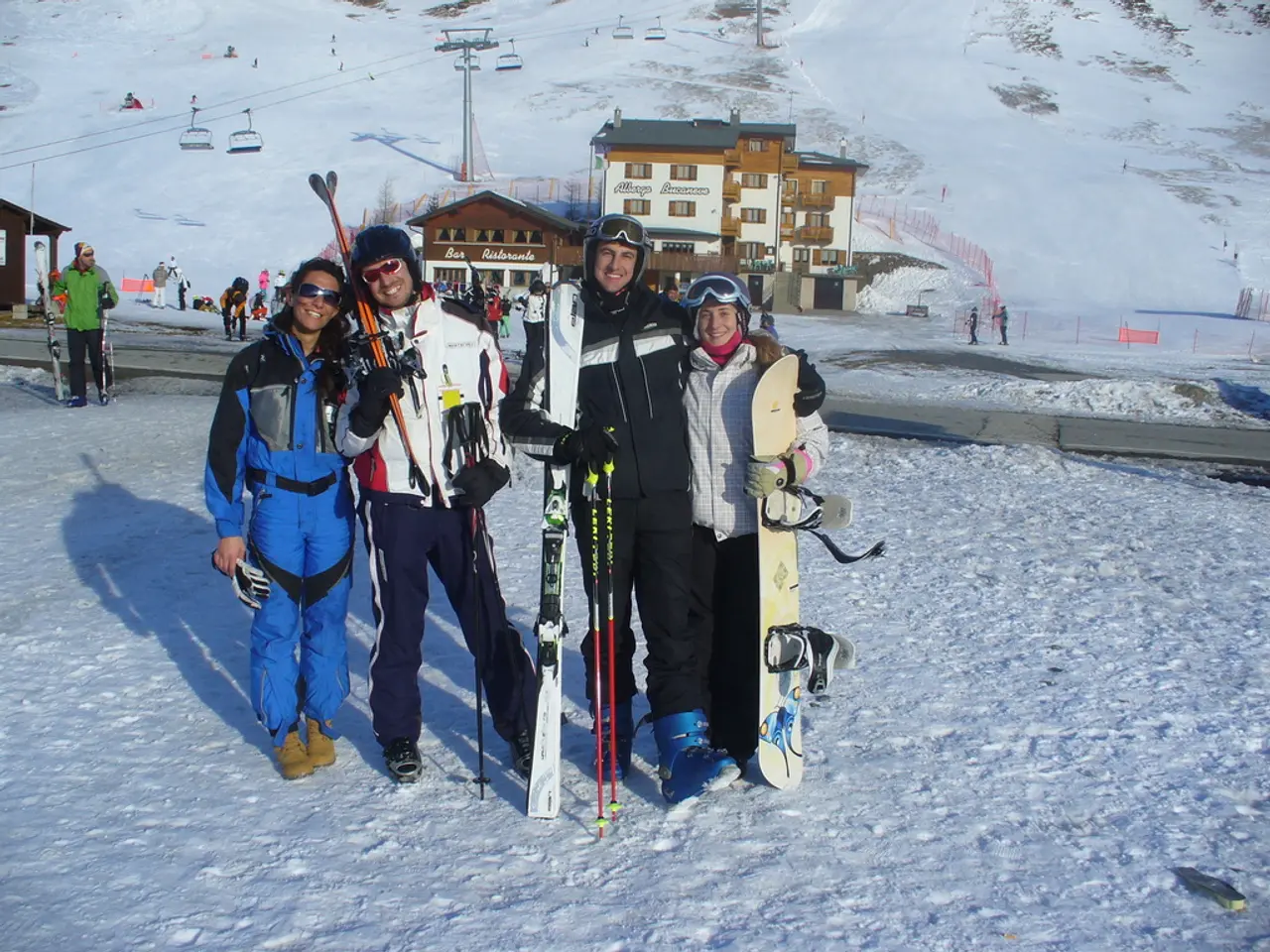 It is a a vacation destination there are four people posing for a photo they are holding skating...