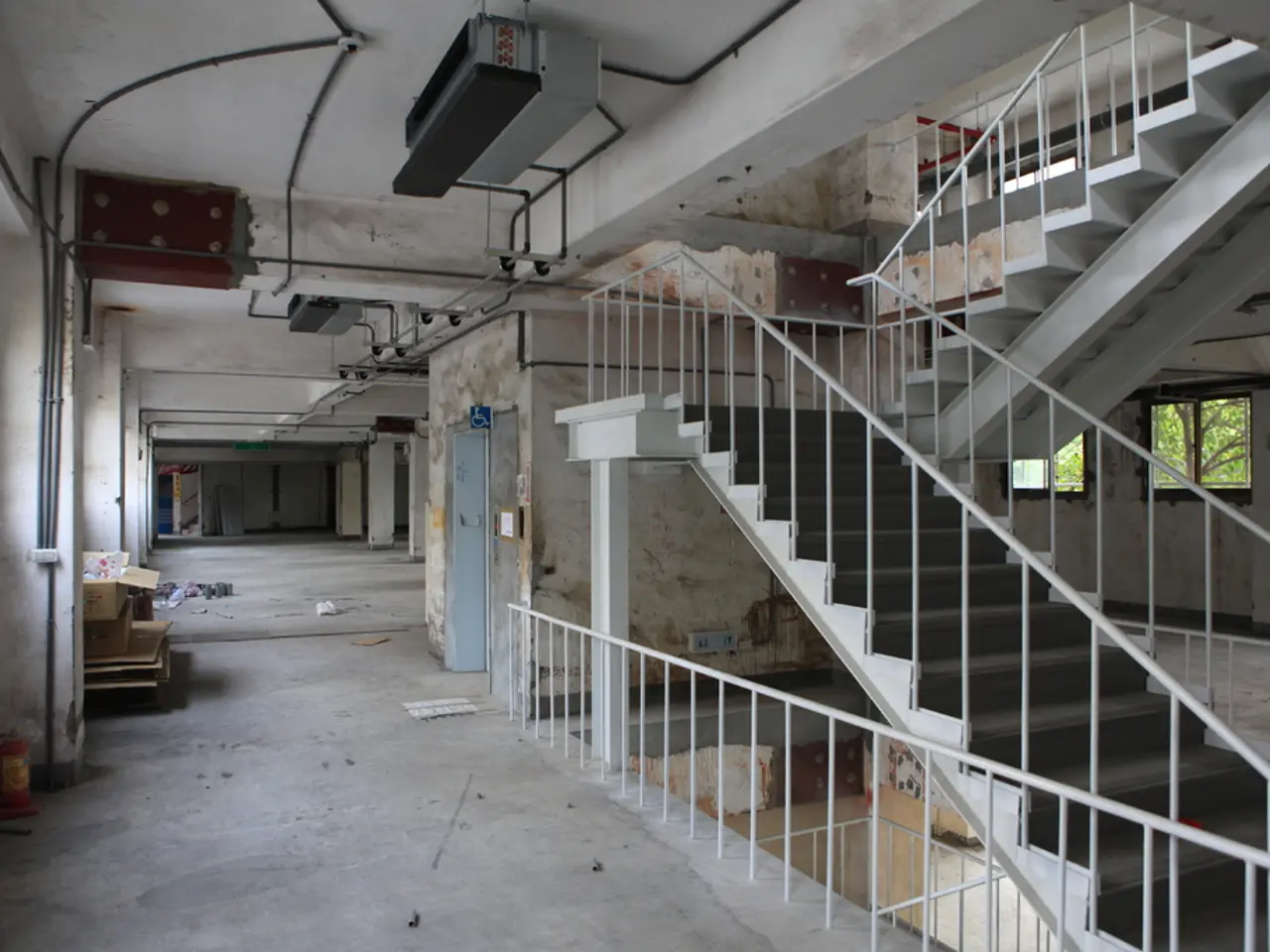 In this image we can see inside view of a building there are some pillars, doors, stairs, windows,...