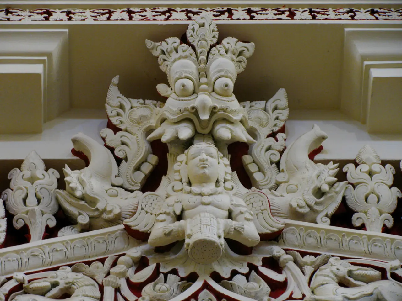 The picture consists of a sculpture on a building. At the top there are floral designs.