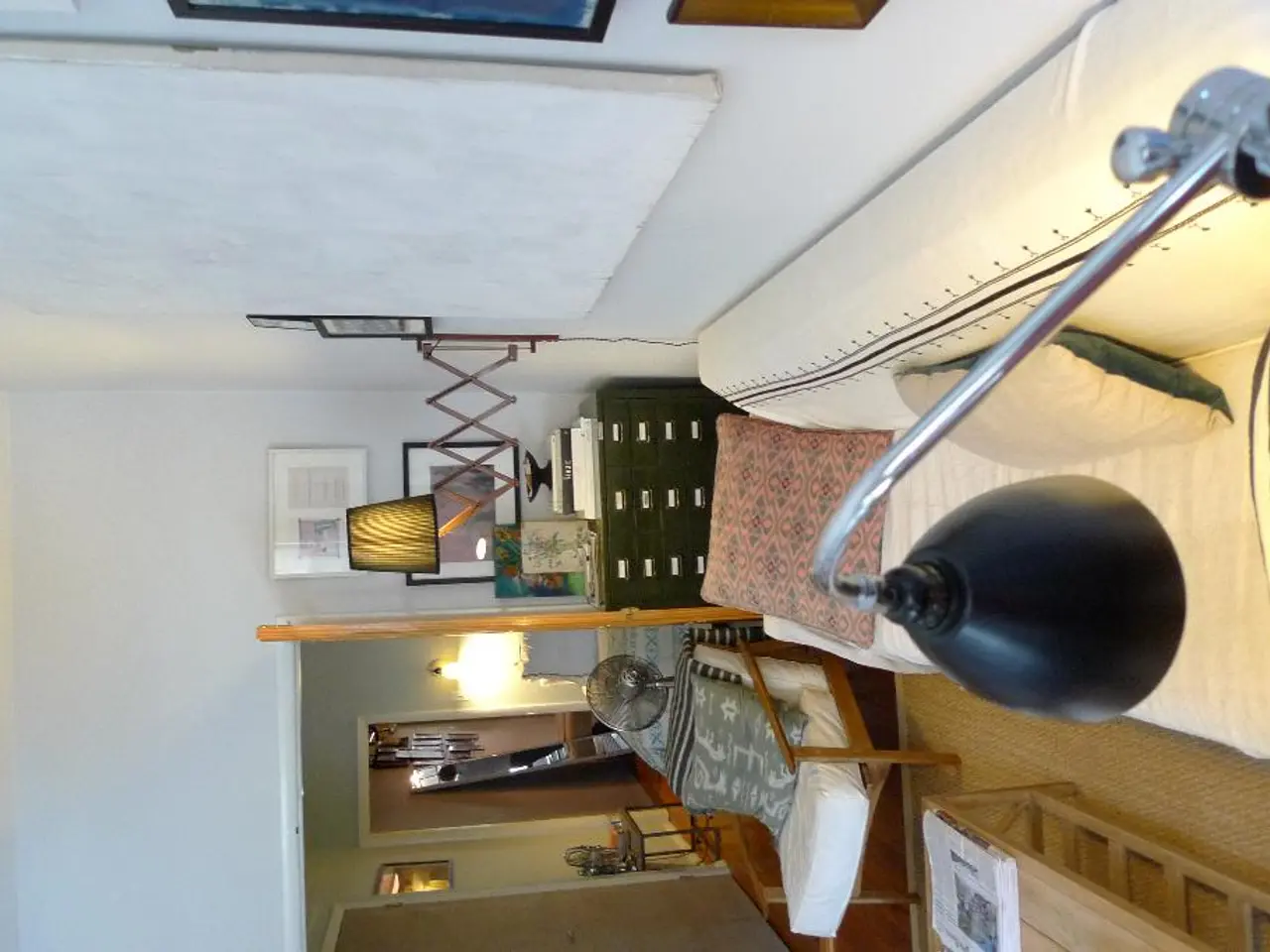 In a room there are lamps, couch, pillows, board, table, books, photo frame, chair, door and other...