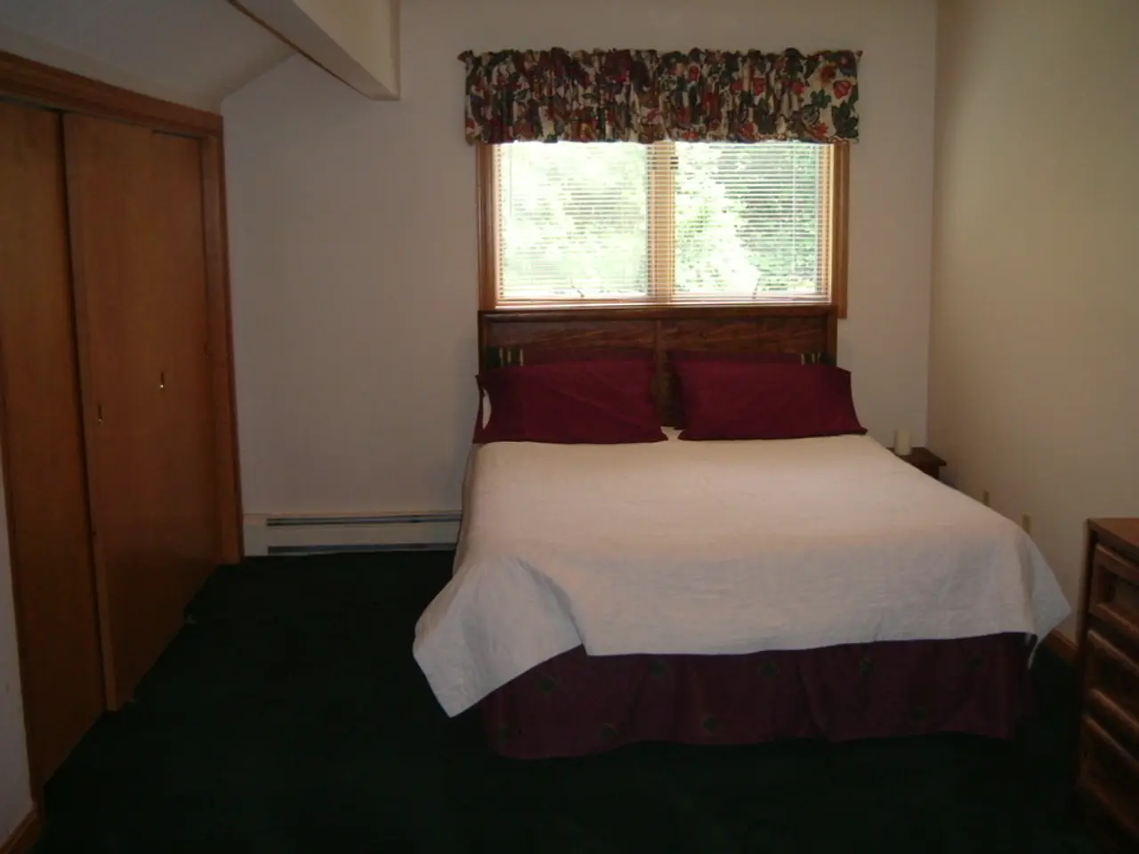 In this image I see a room in which there is a wardrobe, the wall, a window and the bed.