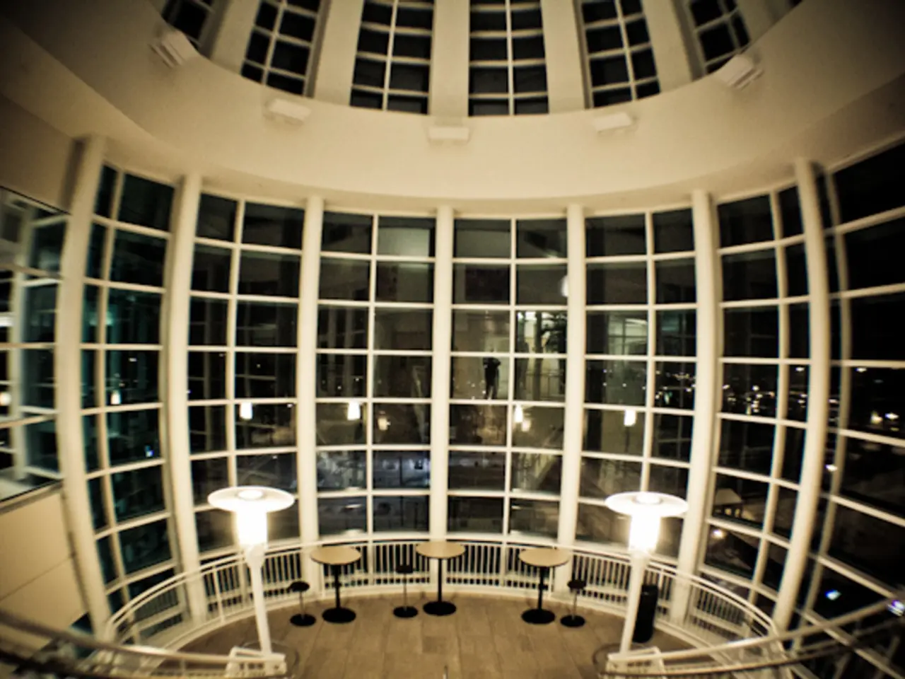 This image is taken indoors. In this image there is an architecture with walls, pillars, railings,...