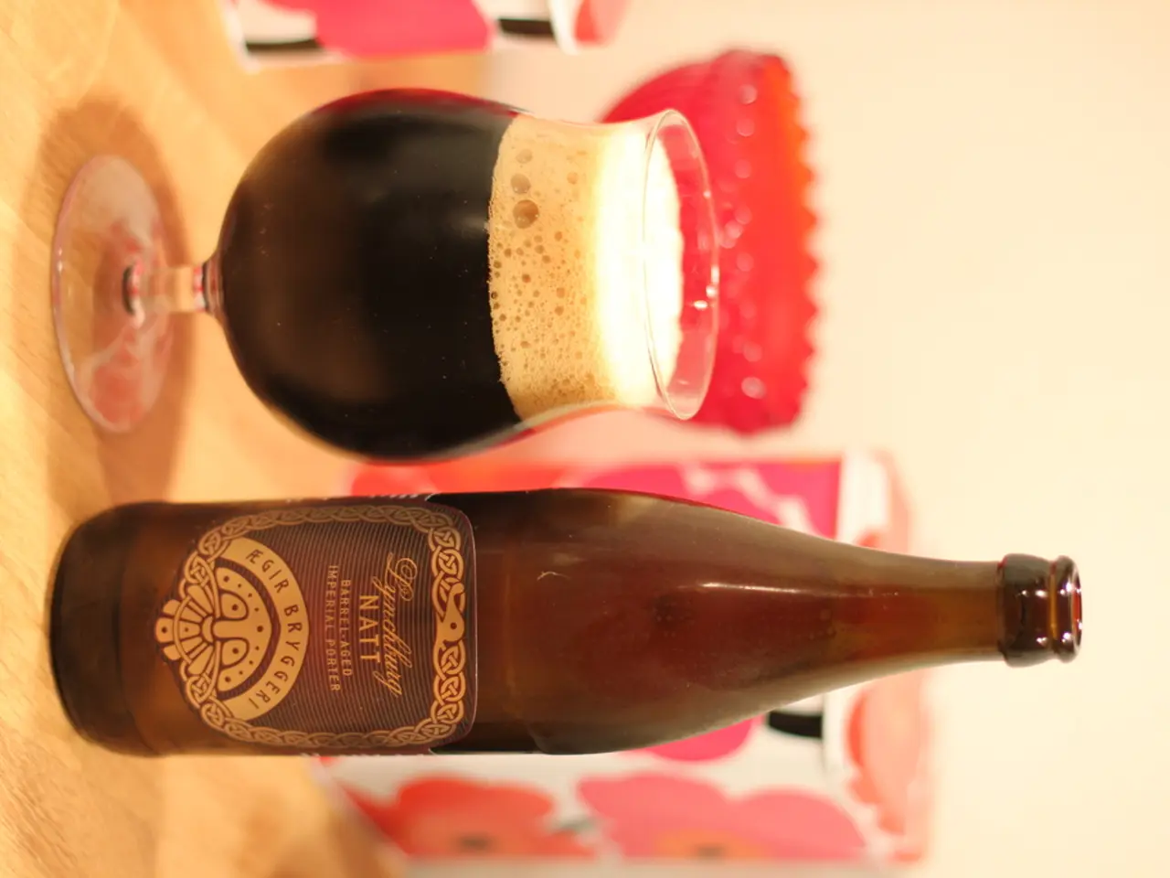 In this image we can see a wooden table where a wine bottle and a glass of wine are kept on it.