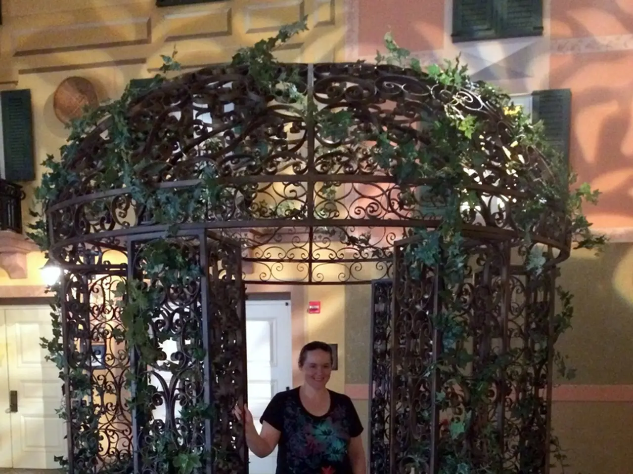 To the front of the image there is a bench. Behind the bench there is an iron pillars with design...