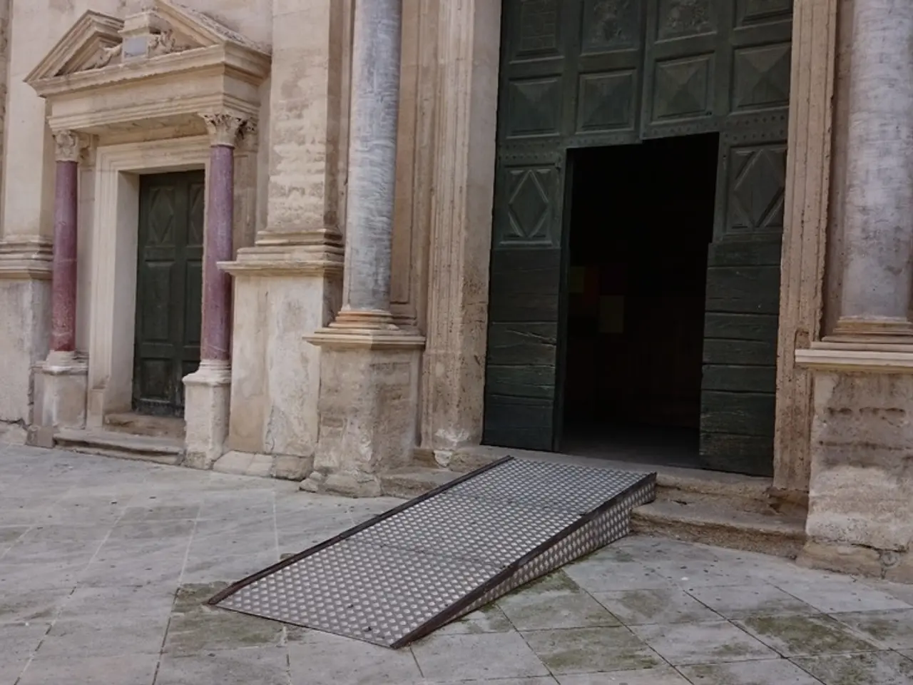 In this image I can see a building and a green colour door over there.