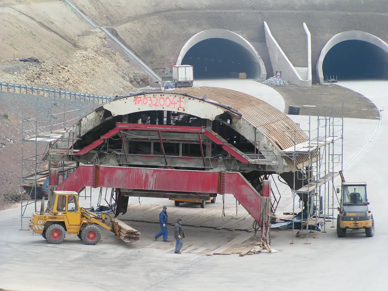 The image shows a large building under construction in the middle of a tunnel, with vehicles on the...