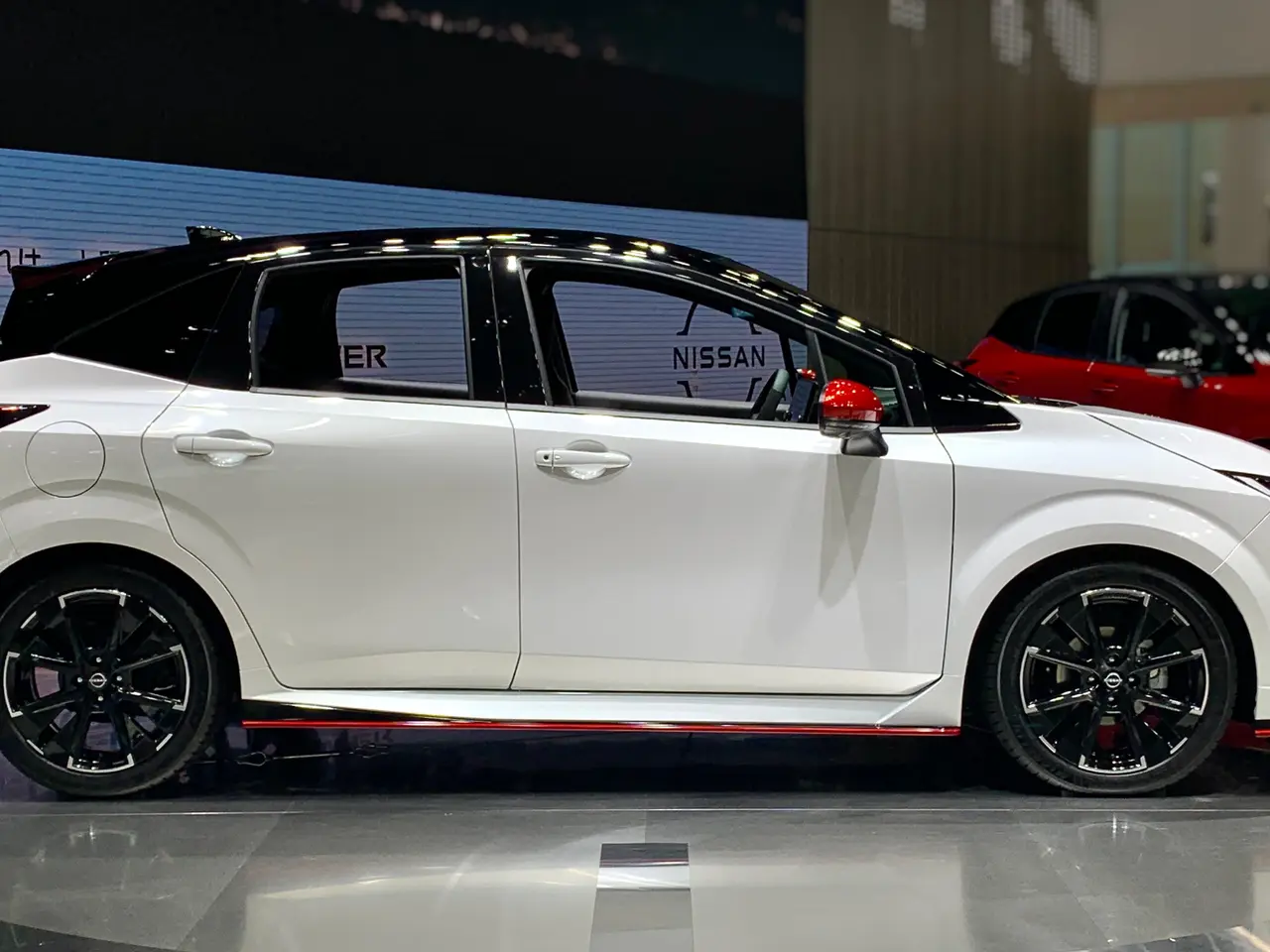 The image shows a white Toyota Corolla Altis on display at an auto show, surrounded by black...