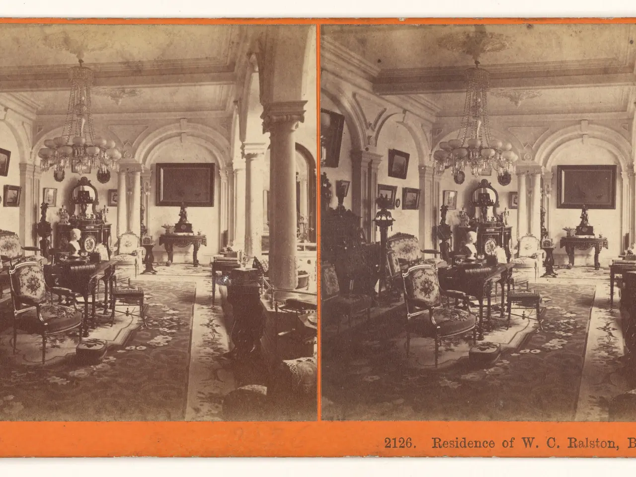 The image shows an old photo of a living room with furniture such as chairs, tables, and...