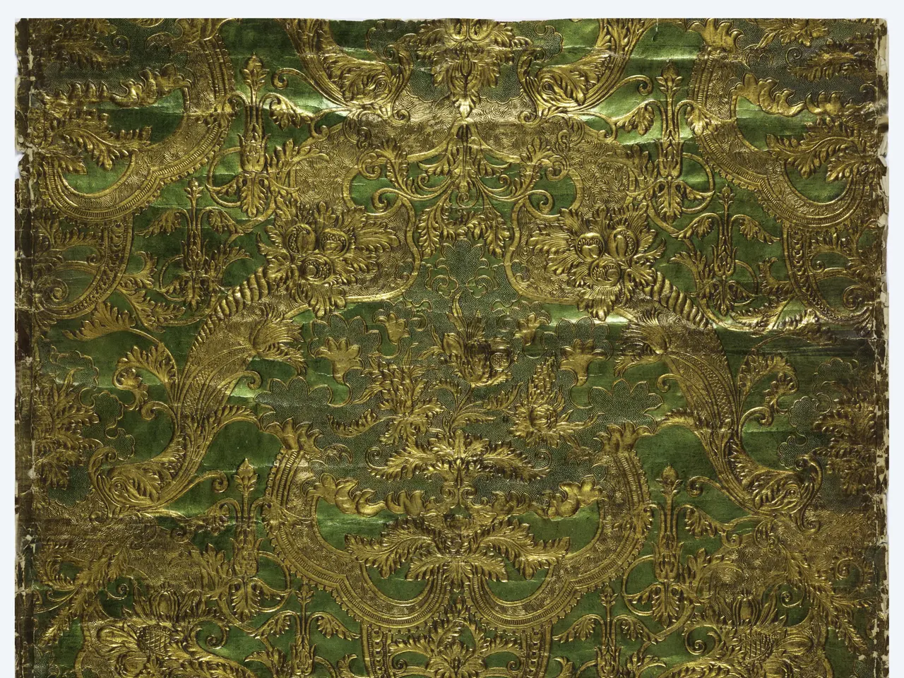 The image shows a green and gold book with a floral design on it, set against a white background....