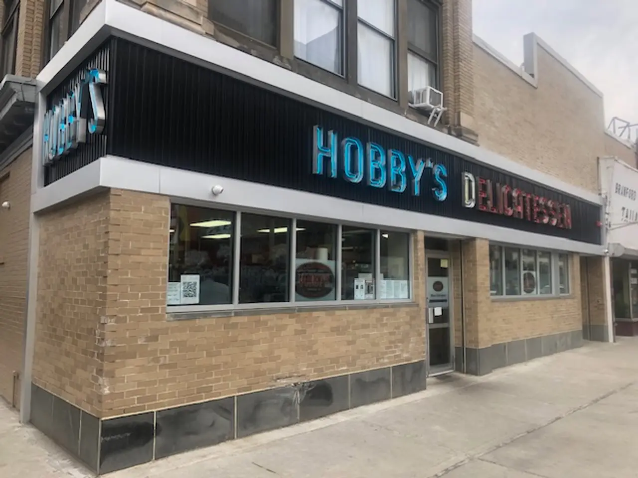 The image shows Hobby's Delicatessen in Chicago, Illinois. It is a building with glass windows and...