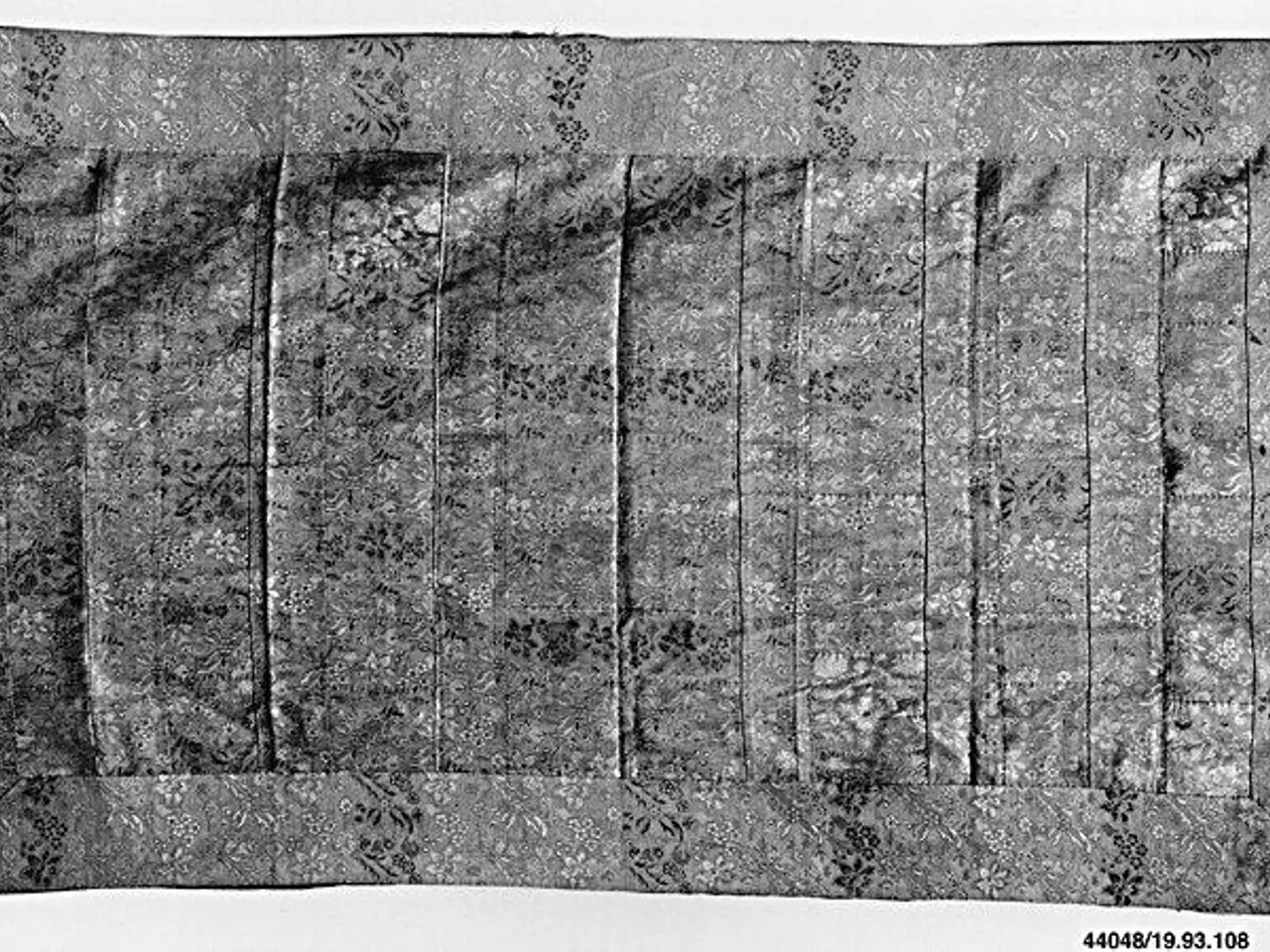 The image shows a black and white photo of a piece of cloth with a pattern on it, which appears to...