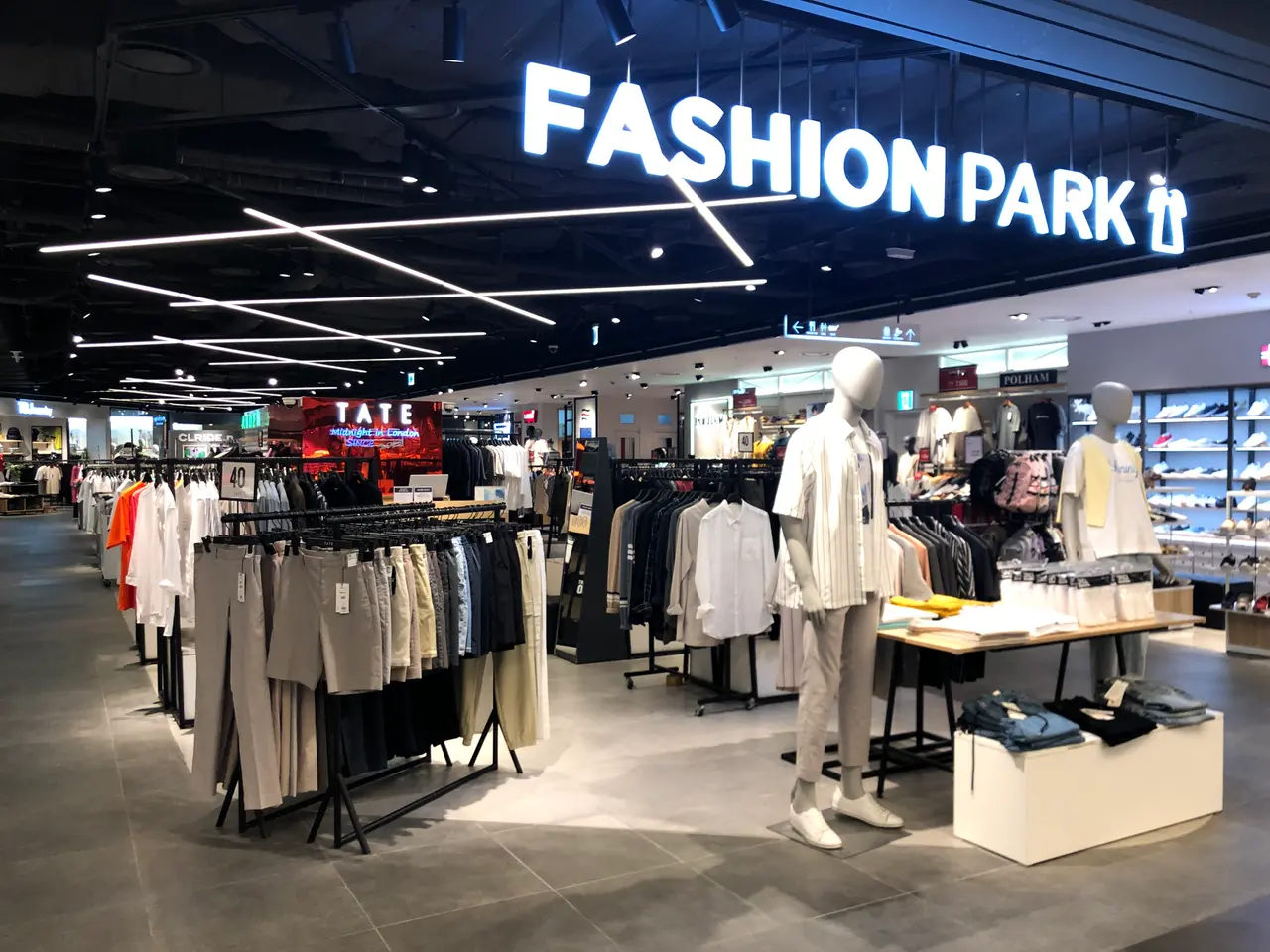 The image shows the inside of a fashion park store with mannequins, clothes hung on hangers, tables...