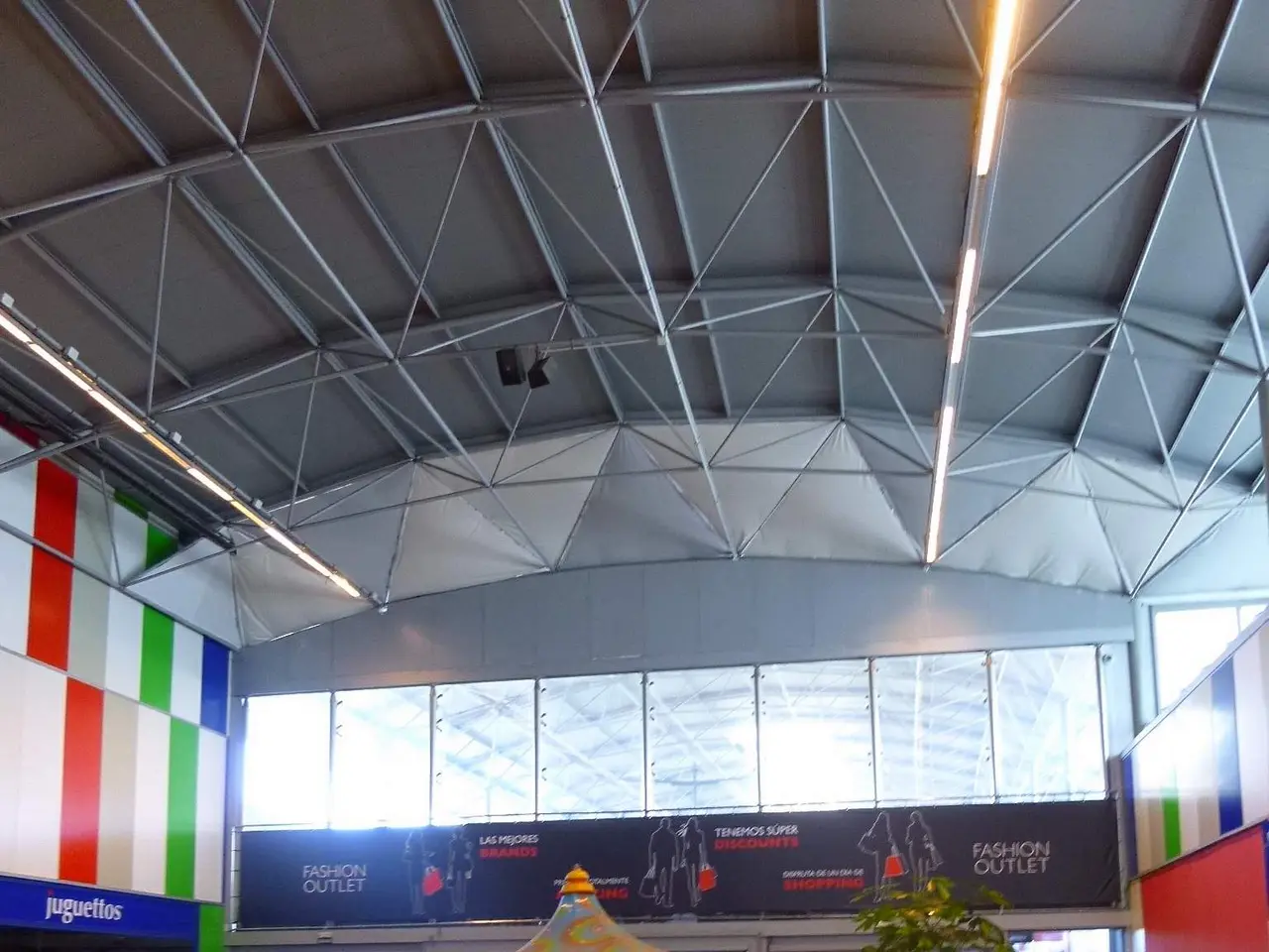 The image shows a large room filled with lots of different types of amusement rides, a plant in a...