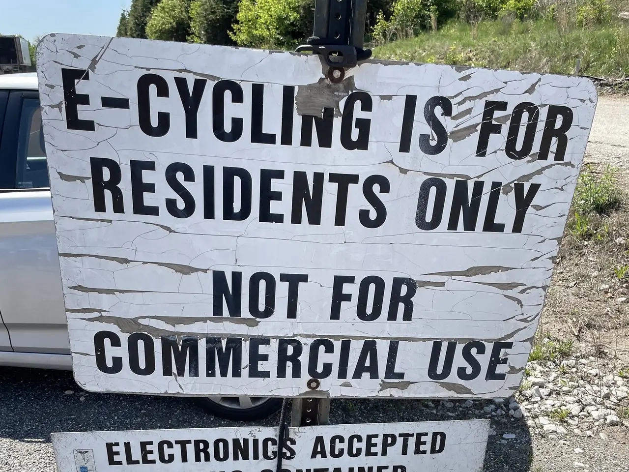 The image shows a sign that reads "e-cycling is for residents only" sitting on the side of a road,...