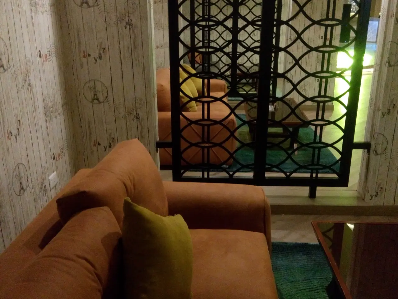 The image shows a living room with a studio couch, pillows, a table with an object on it, a carpet...