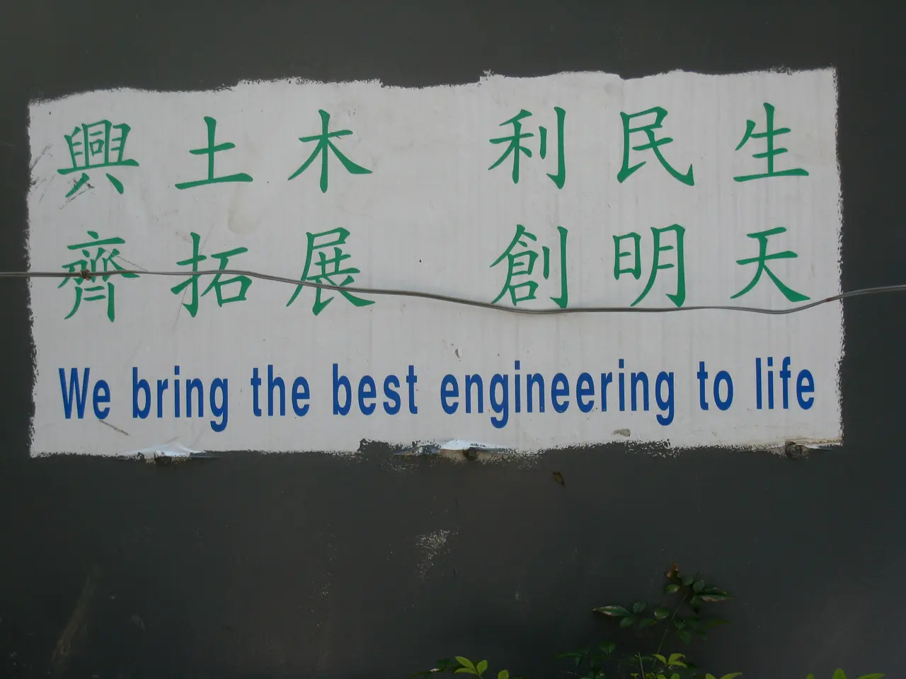 The image shows a sign on the side of a building that reads "We Bring the Best Engineering to Life"...