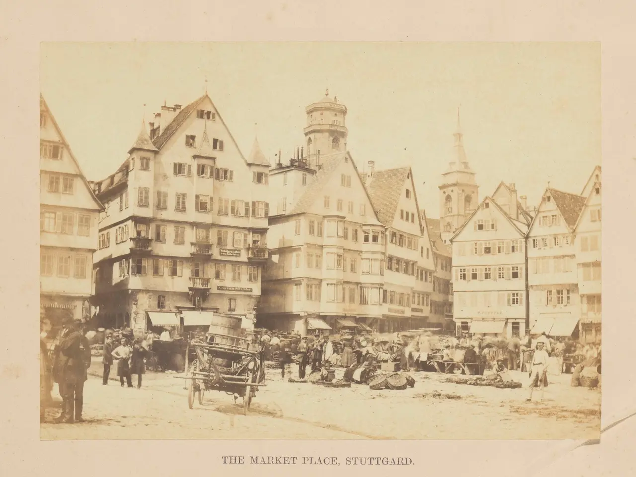 The image shows an old photo of a bustling market place in Stuttgart, Germany. There are many...