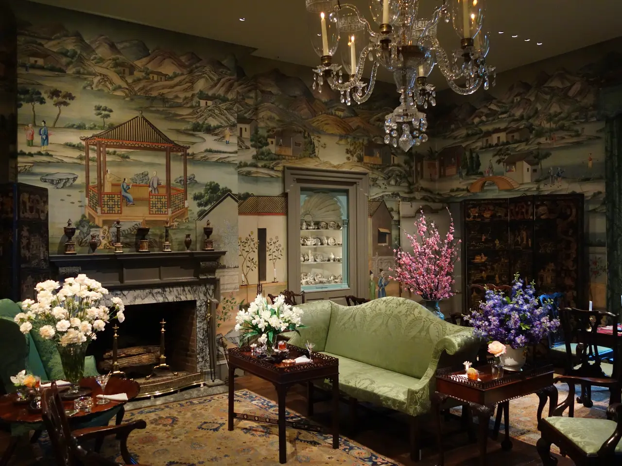 The image shows a living room filled with furniture such as a sofa set, chairs, tables, flower...