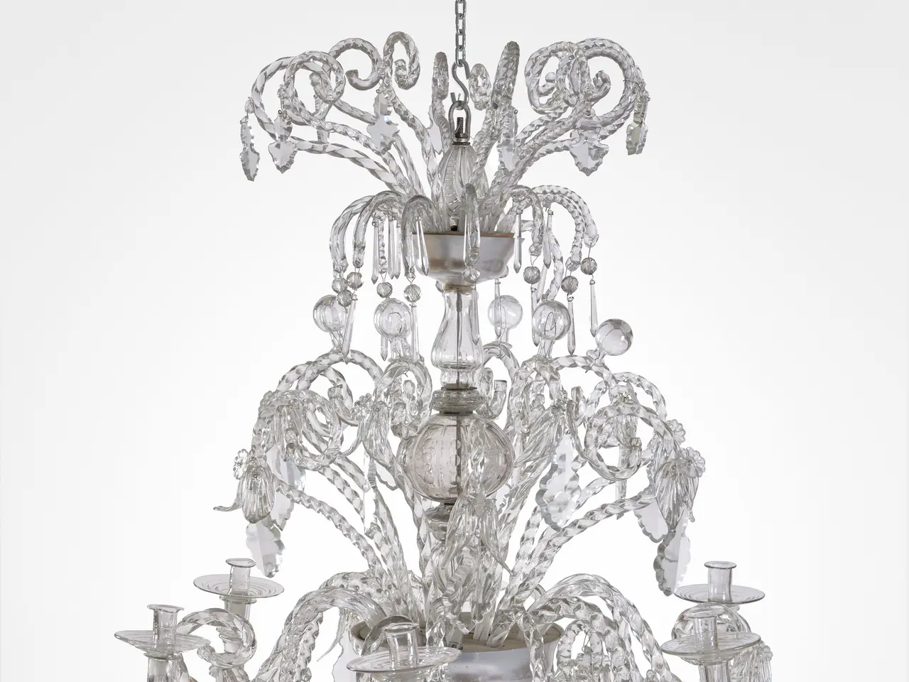 The image shows a large Murano glass chandelier with six lights hanging from the ceiling against a...