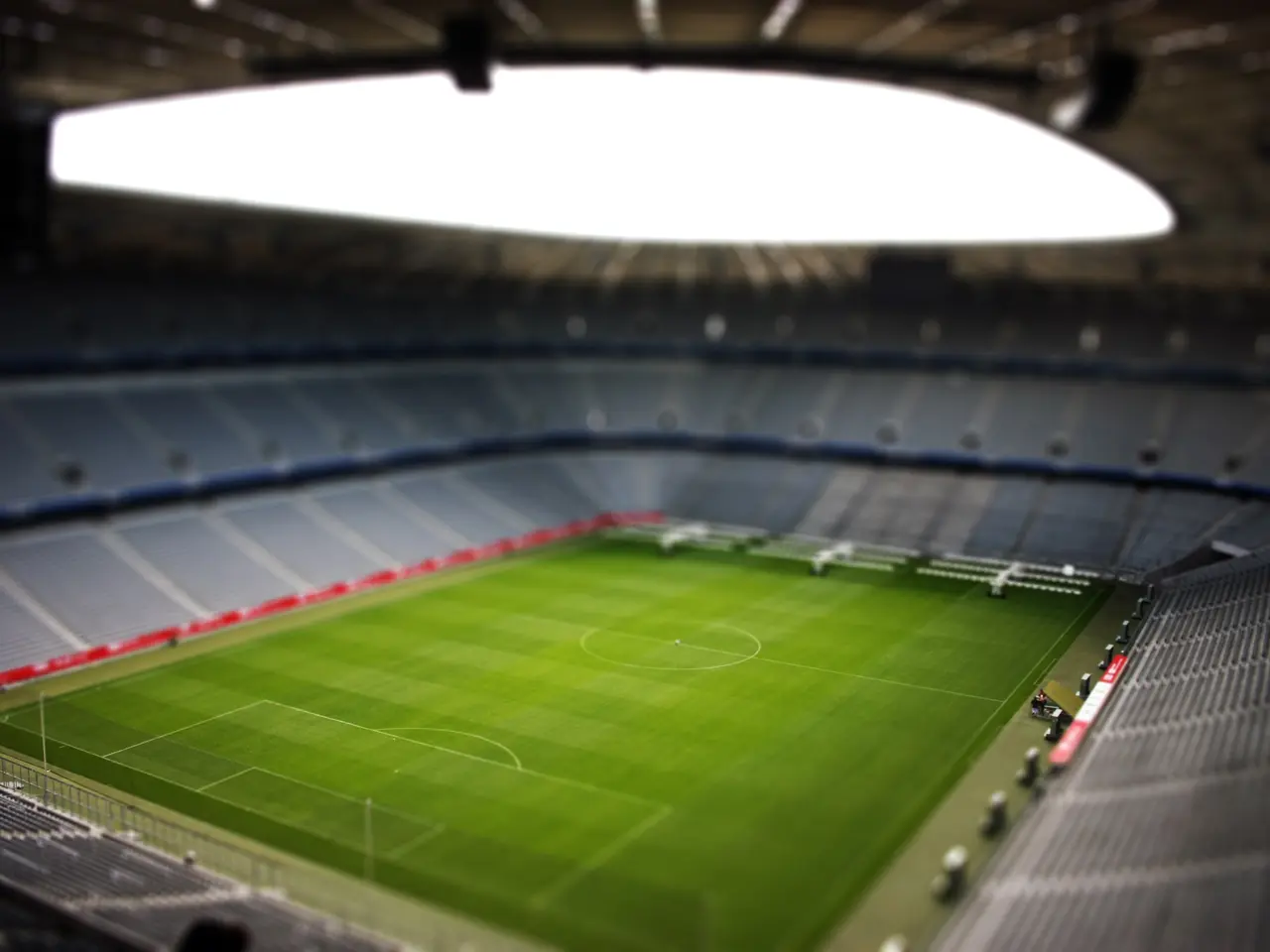The image shows a large stadium with a soccer field in the middle of it, surrounded by chairs and...