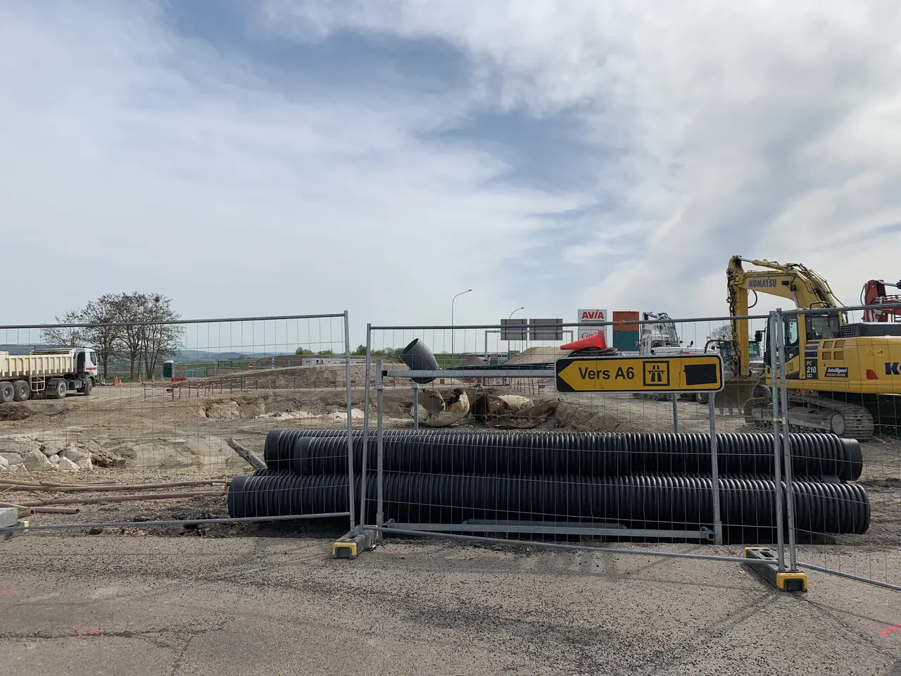 The image shows a construction site with a large pile of black pipes in the middle of it,...