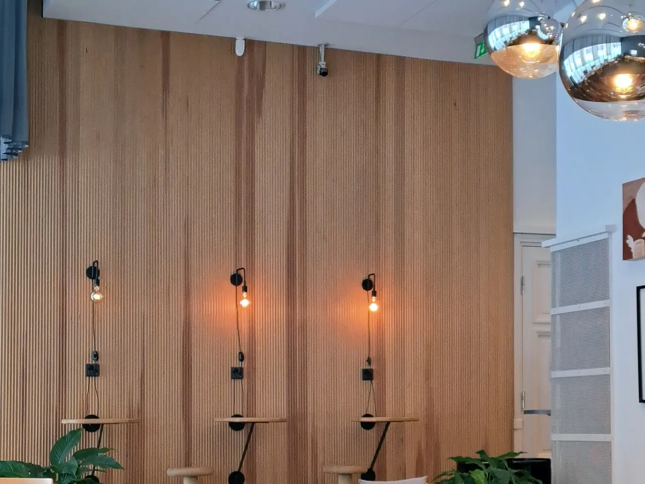 The image shows a room filled with lots of chairs and tables, cushions on the sofas, houseplants,...