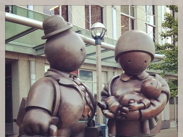 In this image, we can see sculptures in front of the building. There is a pole in the middle of the...