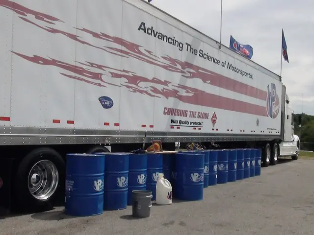 In this image we can see truck, barrels. In the background we can see trees, sky and clouds.