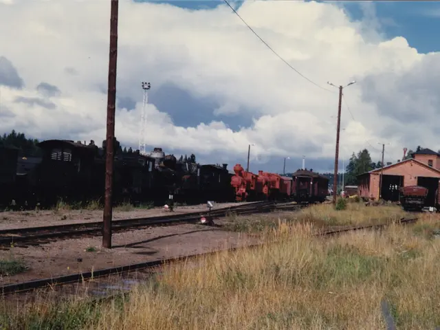 There are railway tracks. Near to that near to that there is grass. There are light poles. In the...