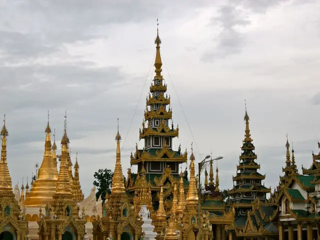 In this image I can see many buildings in green and gold color, background I can see few light...