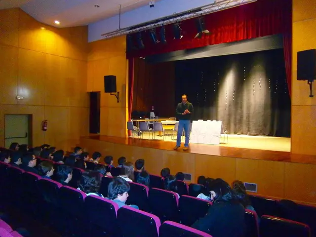 The given picture is consists of an auditorium as there is a person on the stage at the center of...