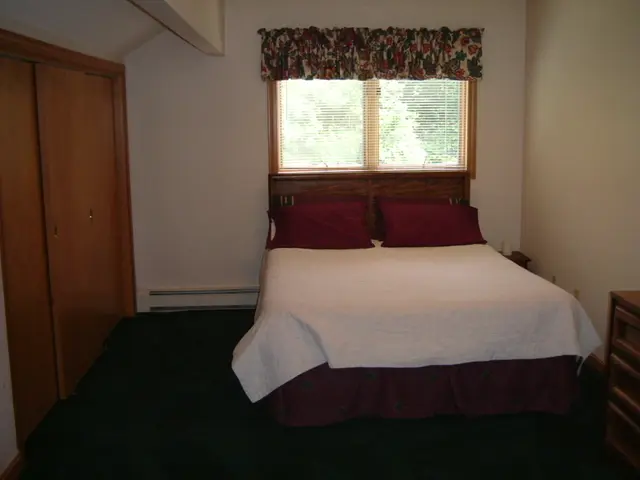 In this image I see a room in which there is a wardrobe, the wall, a window and the bed.