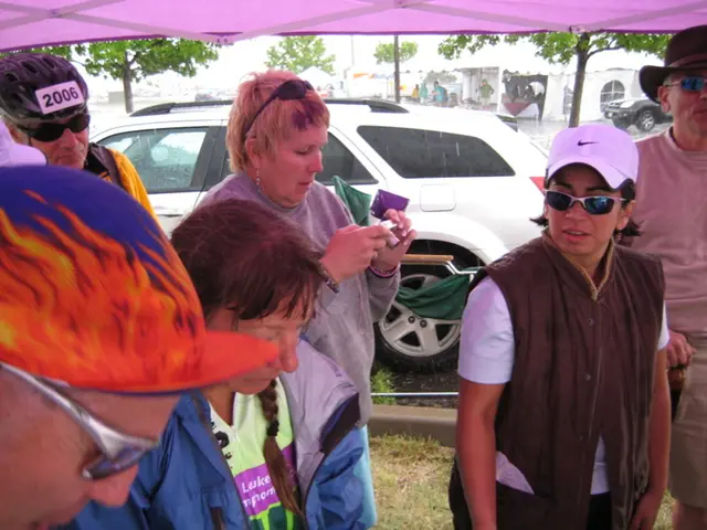 A group of people are standing under the shelter and behind them it is raining on the road and a...