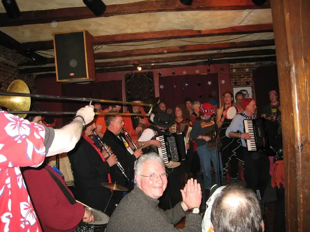 This picture shows the inner view of a building. There are some people sitting, three curtains...