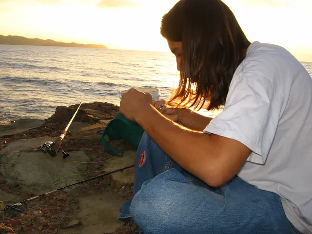 In this picture we can see a girl wearing white t-shirt is sitting at the beach side and holding...