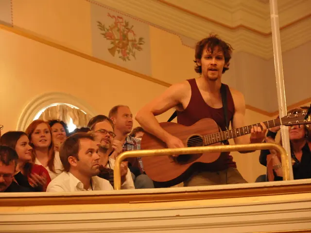 In this picture we can see a group of people sitting and enjoying the music. In center a man...