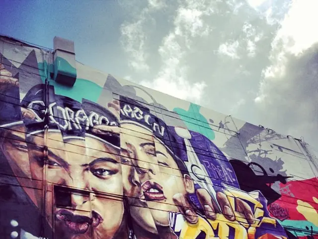 In this picture there is graffiti on the wall and we can see clouds in the sky.