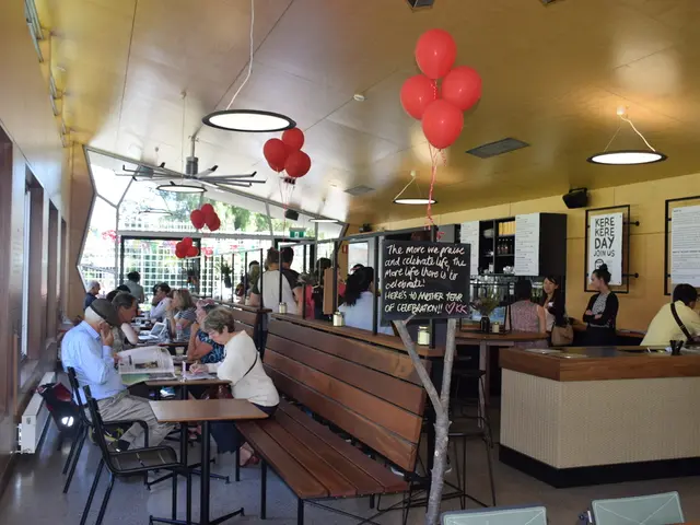 This is a picture of restaurant. Here we can see balloons, lights , boards. Few persons are sitting...