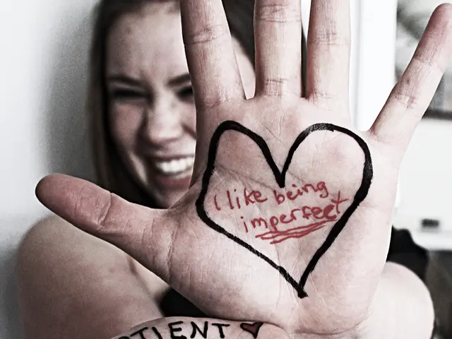 In the middle of the image a girl is standing and she is showing her palms. There is a text on her...