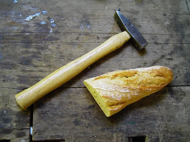 In this image we can see a hammer and a food item on a wooden platform.