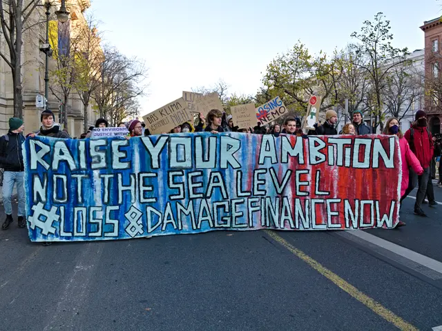The image shows a group of people walking down a street, holding a banner that reads "Raise Your...