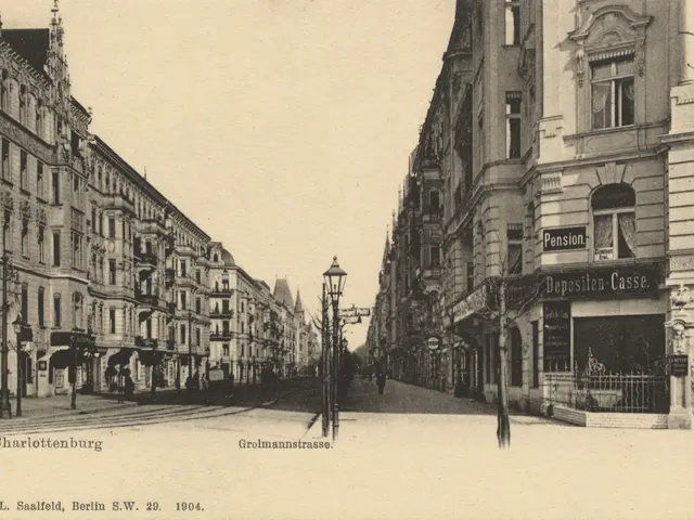 The image shows an old black and white photo of a city street with buildings, street poles, street...