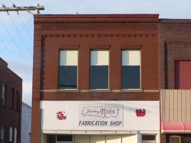 The image shows a brick building with a sign that reads "Fabrication Shop" on the side of it,...