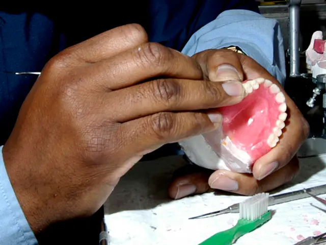 The image shows a person holding a denture in their hands, with a toothbrush and other tools on the...