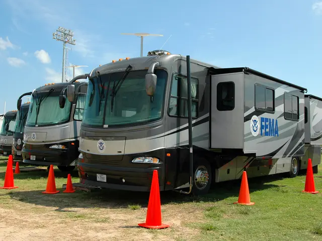 The image shows a group of RVs parked next to each other in a field, surrounded by orange traffic...