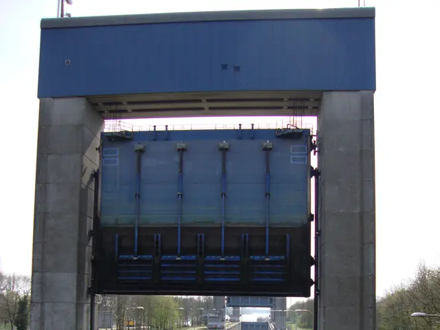 The image shows a boat going through a lock on a river, with a bridge in the background, traffic...
