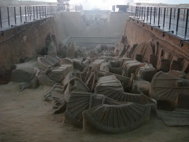 The image shows a large pile of sand sculptures in a room with a wall in the background, railings...